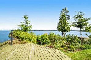 Eine Holzterrasse mit Blick auf einen See und Bäume.