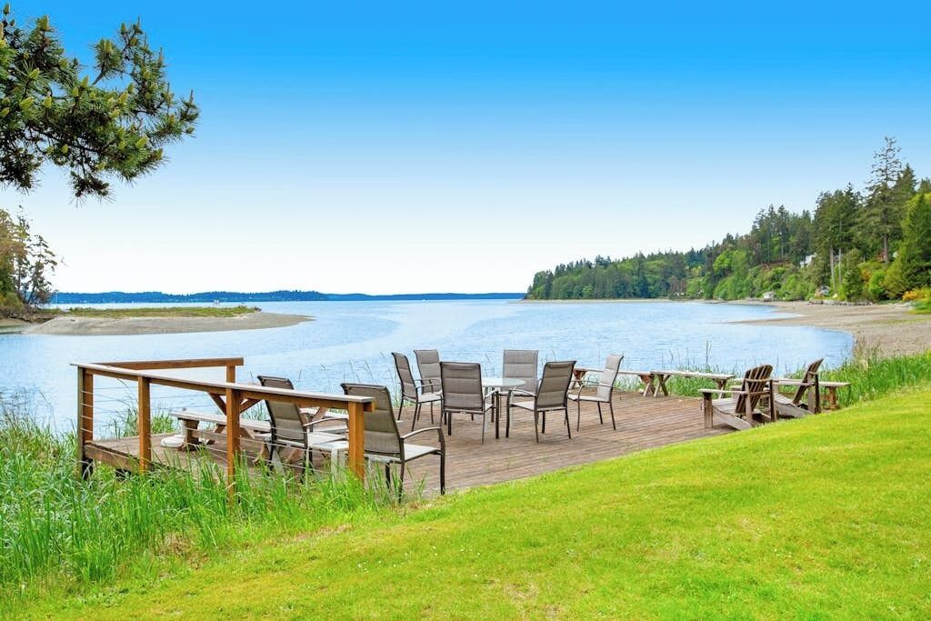 Een terras aan het meer met buitenmeubels en uitzicht op het water.