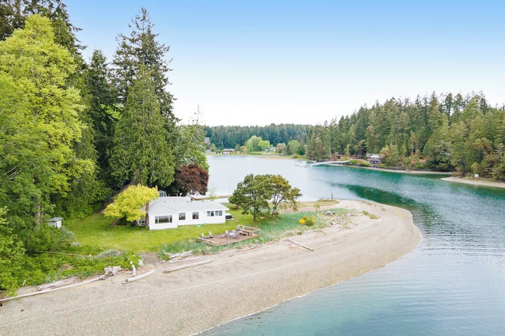A lakeside property with a house, a dock, and a sandy beach.