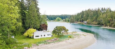 A lakeside property with a house, a dock, and a sandy beach.