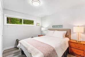 Una camera da letto con un letto, comodini, una finestra e un cartello appeso al muro.