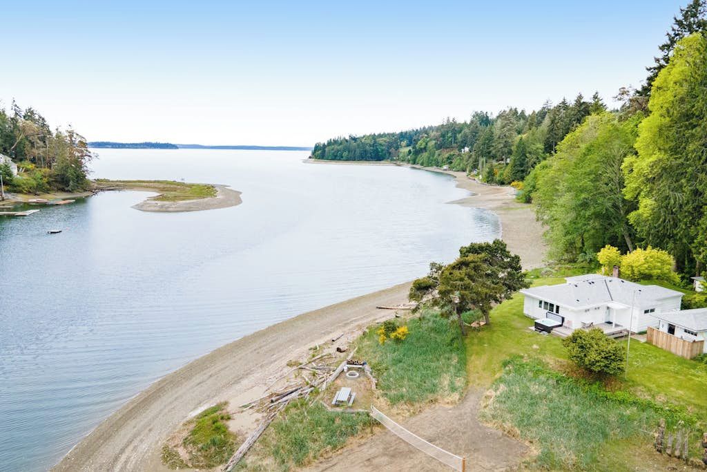 Une propriété au bord du lac, comprenant une maison, un quai et une plage de sable.