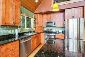 A modern kitchen with wooden cabinets, stainless steel appliances, and a granite countertop. - 1BR Bayview Dog Friendly - Fireplace (Brinnon)
