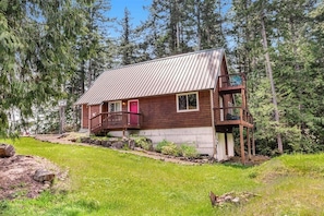A cabin with a metal roof, wooden exterior, and a balcony. - 1BR Bayview Dog Friendly - Fireplace (Brinnon)
