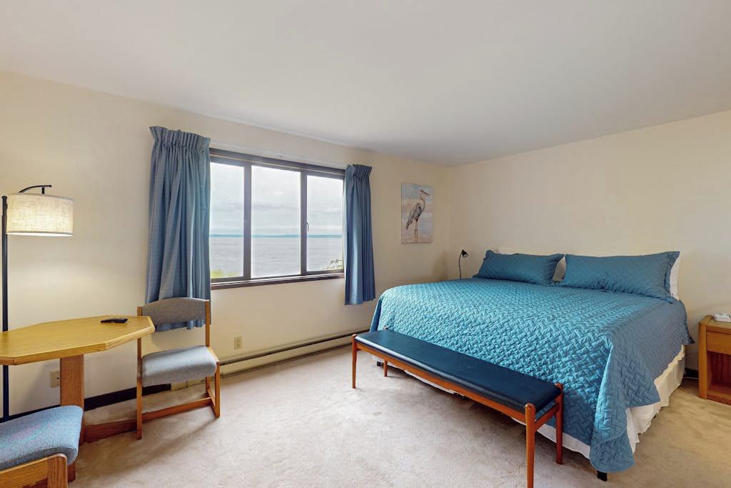 A bedroom with a bed, a desk, a chair, and a bench.