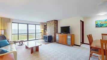 Habitación de hotel con balcón, televisión, mesa de comedor y sofá.