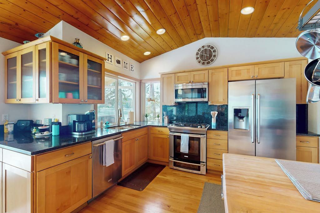 Una cocina moderna con armarios de madera, electrodomésticos de acero inoxidable y un reloj en la pared.