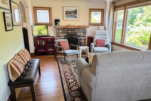 Een woonkamer met een open haard, een bank, een fauteuil en een televisie.