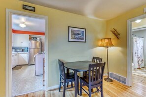 A dining area with a table and chairs, a lamp, and a kitchen visible through an open doorway. - Large 2BR Northeast Seattle - Deck - Washer Dryer (Seattle)