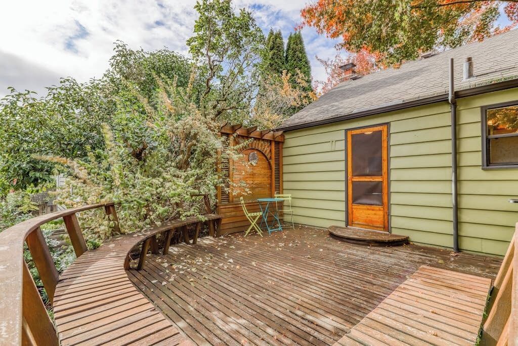A wooden deck with a wooden pergola, a small table, and a chair.