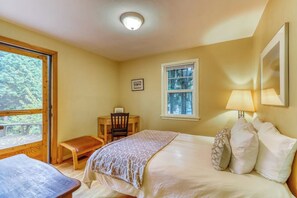 A bedroom with a bed, a desk, a chair, a window, and a door leading to an outdoor area. - Large 2BR Northeast Seattle - Deck - Washer Dryer (Seattle)