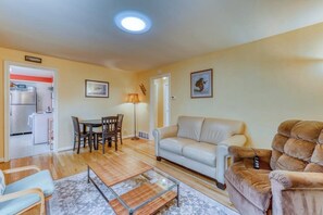 A living room with a sofa, armchair, coffee table, and dining area. - Large 2BR Northeast Seattle - Deck - Washer Dryer (Seattle)