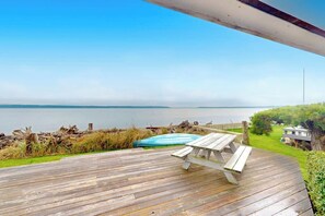 A wooden deck with a picnic table overlooking a body of water.