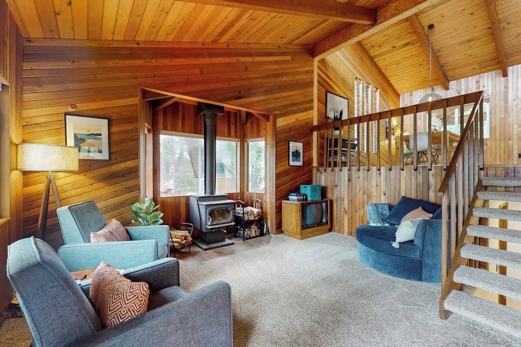 A cozy cabin interior with a wooden interior, a fireplace, a television, and a staircase.