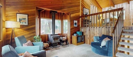 A cozy cabin interior with a wooden interior, a fireplace, a television, and a staircase.