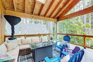 A covered outdoor seating area with a sofa, chairs, and a table. - 3BR Lakefront Gas Grill - Deck - Firepit (Hoodsport)
