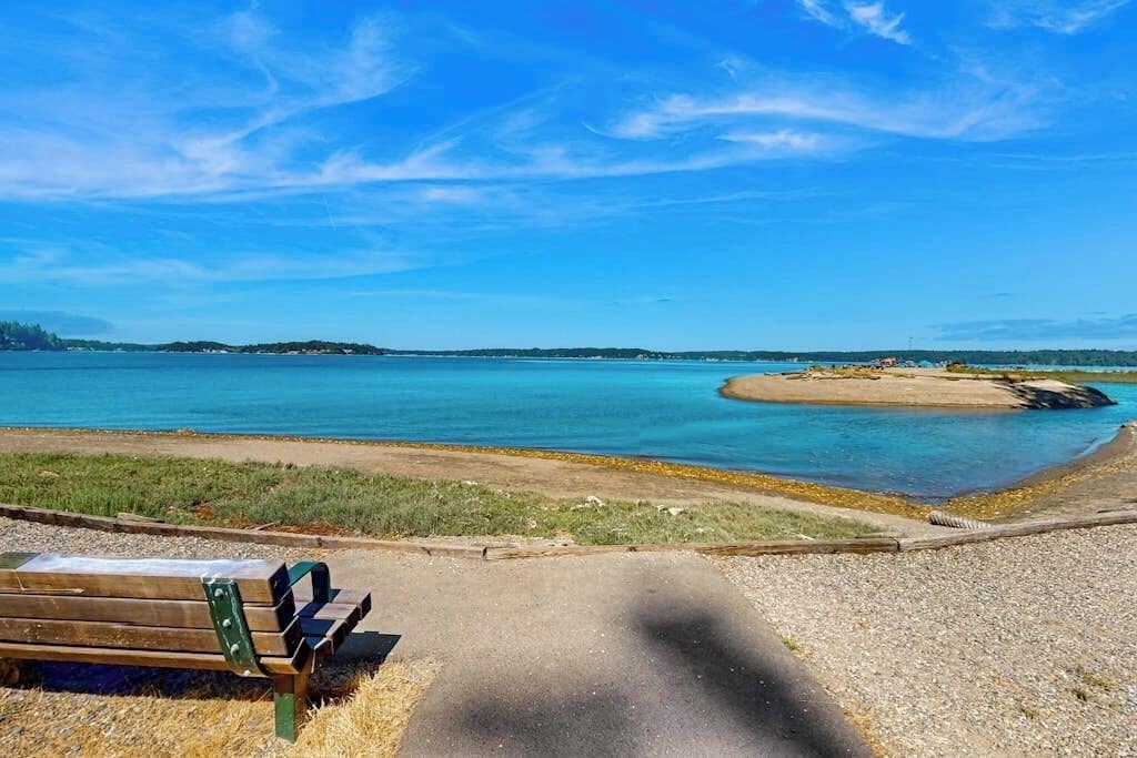 A bench by a body of water with a clear sky.