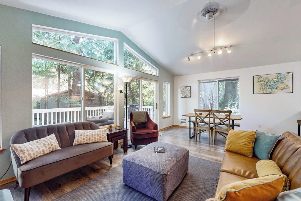 A spacious living room with large windows, a dining area, and a cozy seating arrangement.