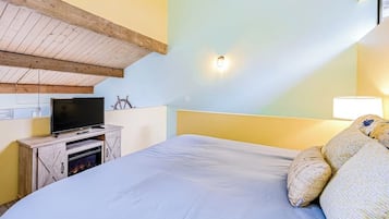 Ein Schlafzimmer mit einem Bett, einem Fernseher auf einer Holzkommode und einer Wandleuchte.
