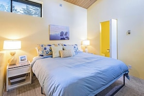 Une chambre à coucher avec un lit, deux tables de chevet avec des lampes, un tableau au mur et une porte.