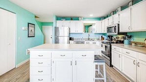 Una cocina moderna con armarios blancos, electrodomésticos de acero inoxidable y una isla central.