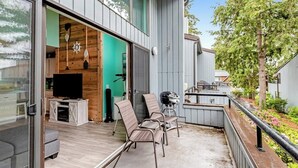Un patio al aire libre con televisor, asientos y zona de barbacoa.