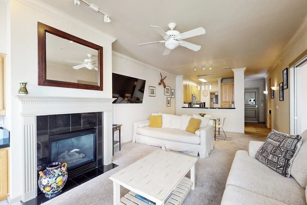 A living room with a fireplace, white sofa, and a ceiling fan.