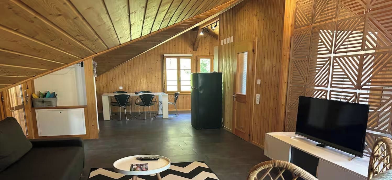 Un intérieur en bois comprenant un téléviseur, un coin salon et un espace repas.