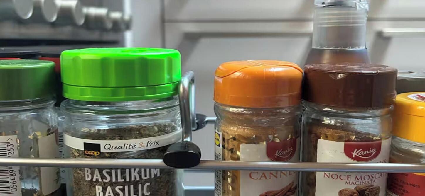 En hylla med olika livsmedel, inklusive burkar med kryddor och smaktillsatser.