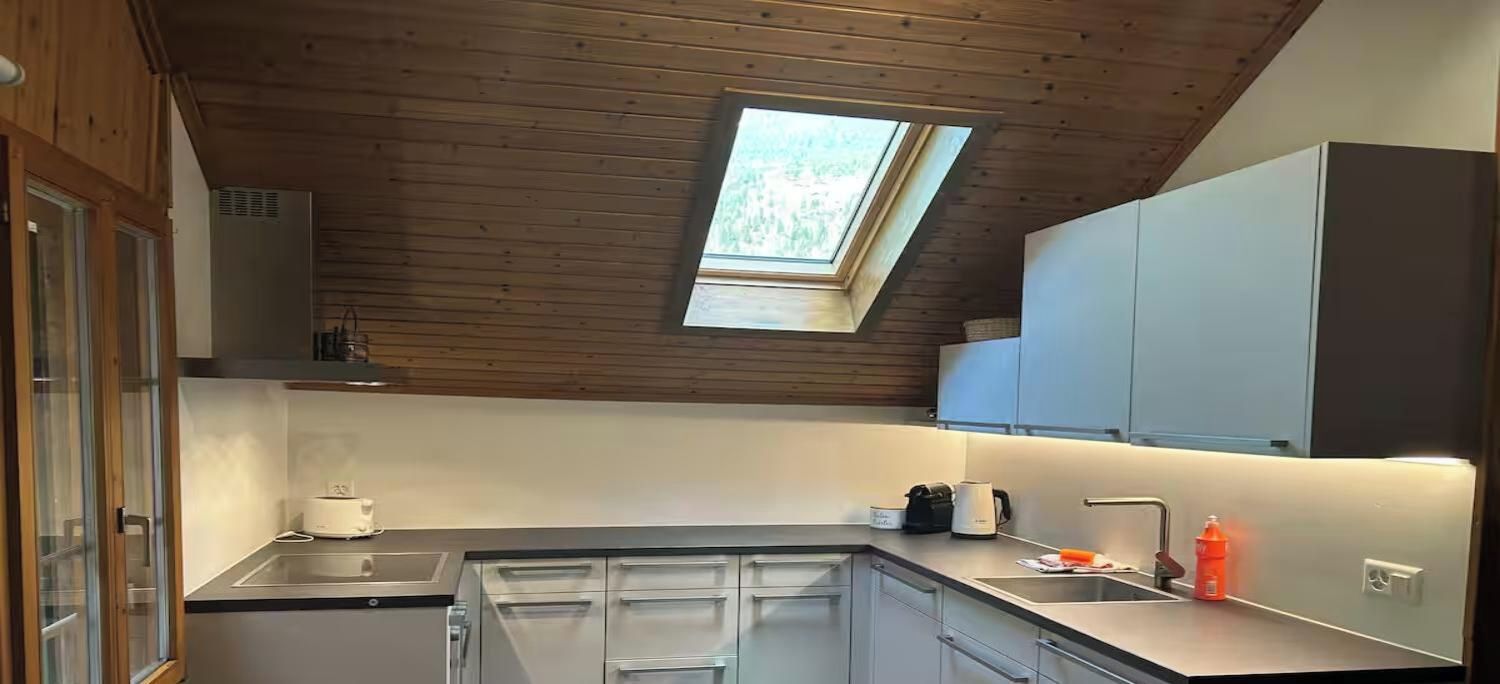 A modern kitchen with a skylight, stainless steel appliances, and white cabinetry.