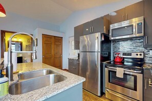 A modern kitchen with stainless steel appliances, granite countertops, and a double sink. - 1BR Cozy Waterfront Studio Rental (Camano Island)