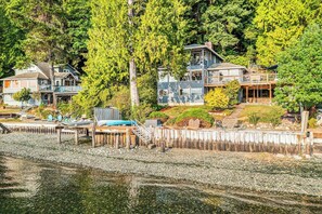 A waterfront property with multiple houses, a dock, and a wooden walkway leading to the water. - 3 BR waterfront home with amazing views and beach (Vashon)