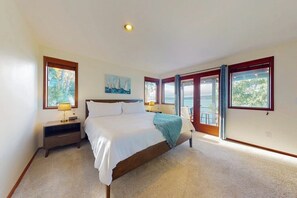 A bedroom with a large bed, two bedside tables, a nightstand, a painting, and a view through the windows. - 3 BR waterfront home with amazing views and beach (Vashon)