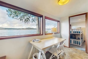 A room with a desk, chair, and bunk beds, overlooking a body of water. - 3 BR waterfront home with amazing views and beach (Vashon)