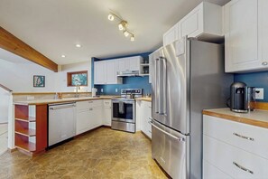 A modern kitchen with white cabinetry, stainless steel appliances, and a stone tile floor. - 3 BR waterfront home with amazing views and beach (Vashon)