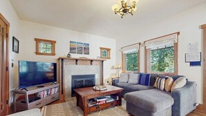 Una sala de estar con chimenea, televisor, sofá y mesa de centro.
