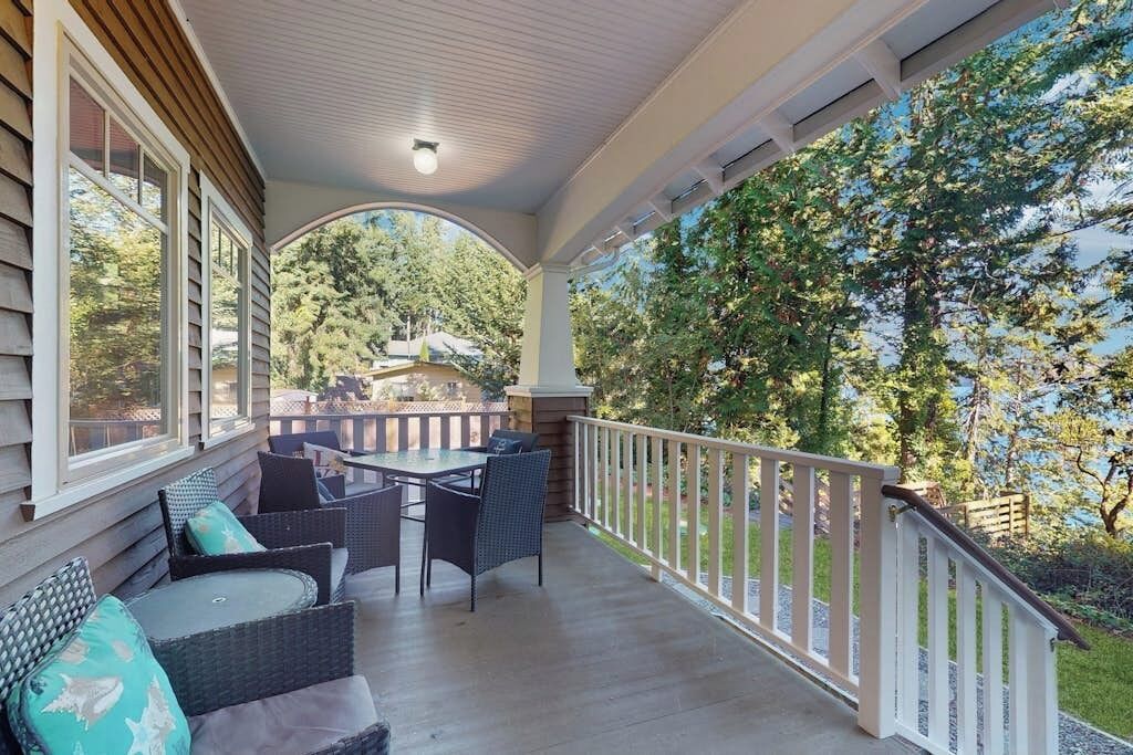 Eine überdachte Veranda mit Gartenmöbeln, einem Geländer und Blick auf einen Garten.
