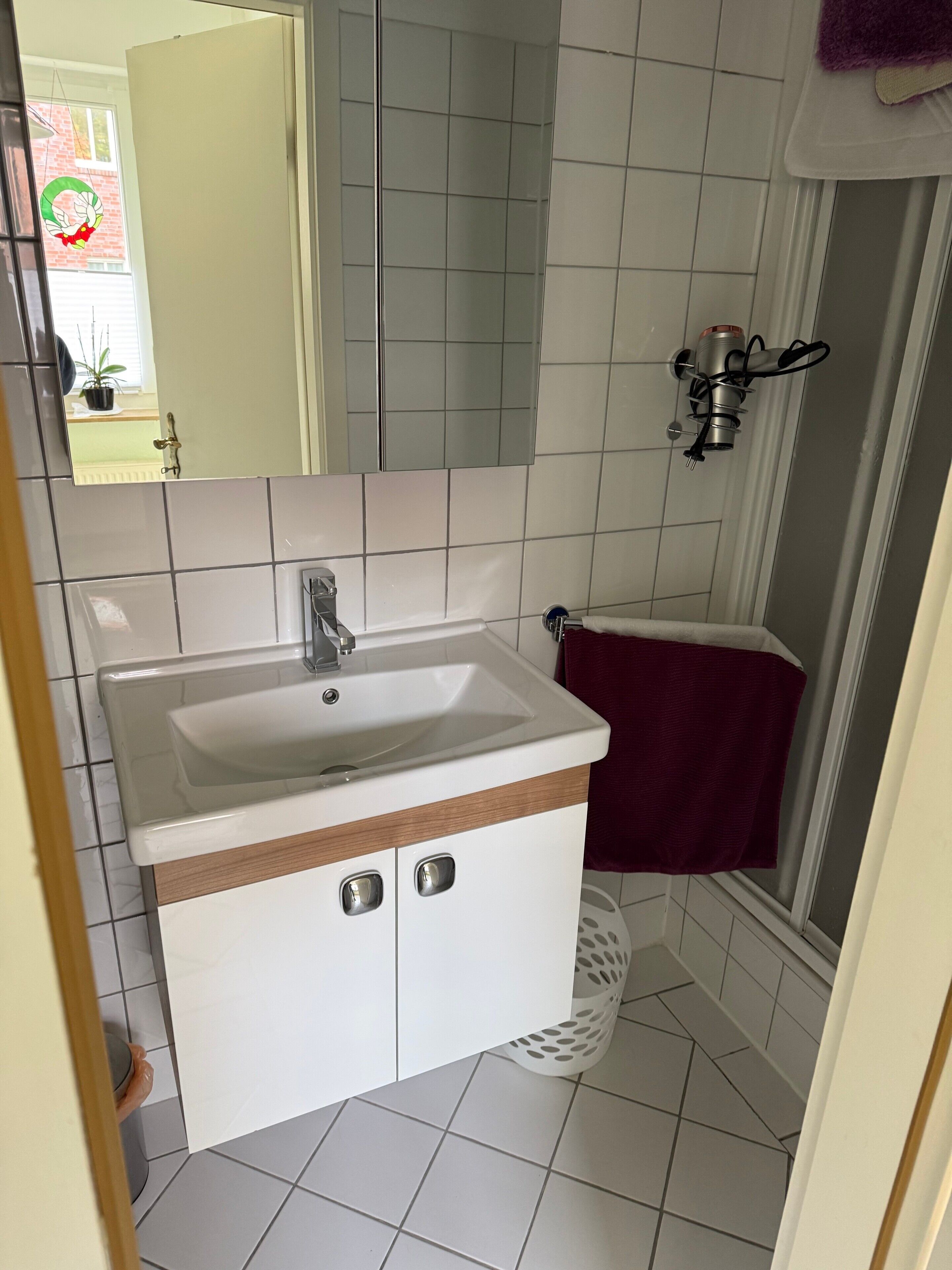 Ein Badezimmer mit Waschbecken, Spiegel und gefliesten Wänden.