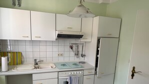 A compact kitchen with white cabinets, a sink, a stove, and a refrigerator.