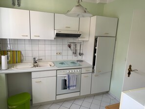 A compact kitchen with white cabinets, a sink, a stove, and a refrigerator.