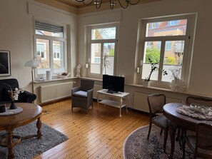 A living room with a television, a dining table, and a sofa.