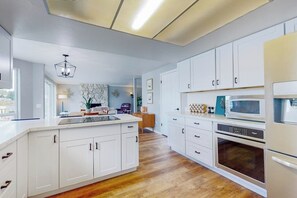 A modern kitchen with white cabinetry, a central island, and built-in appliances. - 4BR dog-friendly with water views & deck (Shelton)