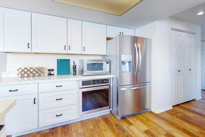 A modern kitchen with white cabinets, stainless steel appliances, and a wooden floor. - 4BR dog-friendly with water views & deck (Shelton)