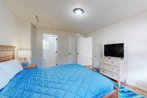 A bedroom with a bed, a dresser, a television, and a door leading to another room. - 4BR dog-friendly with water views & deck (Shelton)