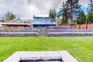 A two-story house with a front porch, a stone retaining wall, and a grassy lawn. - 4BR dog-friendly with water views & deck (Shelton)