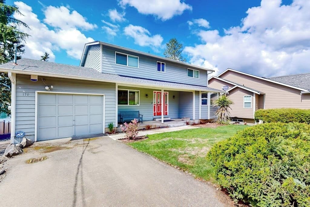 A two-story house with a garage, a covered porch, and a well-maintained lawn.