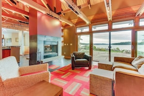 Un amplio salón con chimenea, ventanas grandes y vistas a un lago.