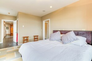 A hotel room with a large bed, a wooden headboard, and a small table. - Spacious 3BR Oceanfront - Chef's Kitchen (Anacortes)