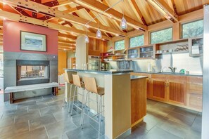 Una cocina moderna con una isla central, taburetes de bar y una chimenea.