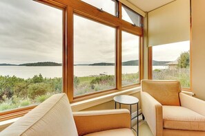 A room with large windows overlooking a lake, two sofas, and a small table. - Spacious 3BR Oceanfront - Chef's Kitchen (Anacortes)